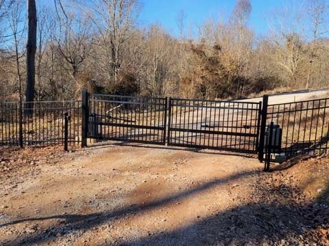 Fence with Metal double swing gate with gate operator installed in West Virginia over a dirt road in West Virginia